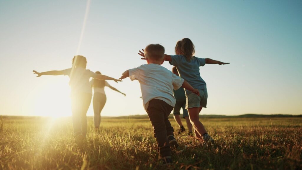 Kinder auf dem Feld und machen eine Fliegerpose.
