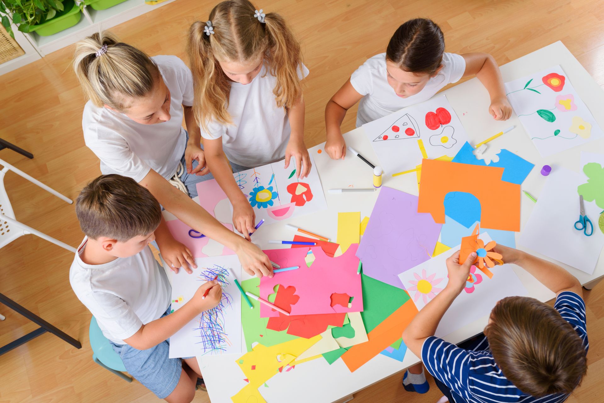 Kleine Kinder sitzen am Tisch und basteln.