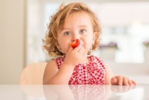 Small child eats a strawberry