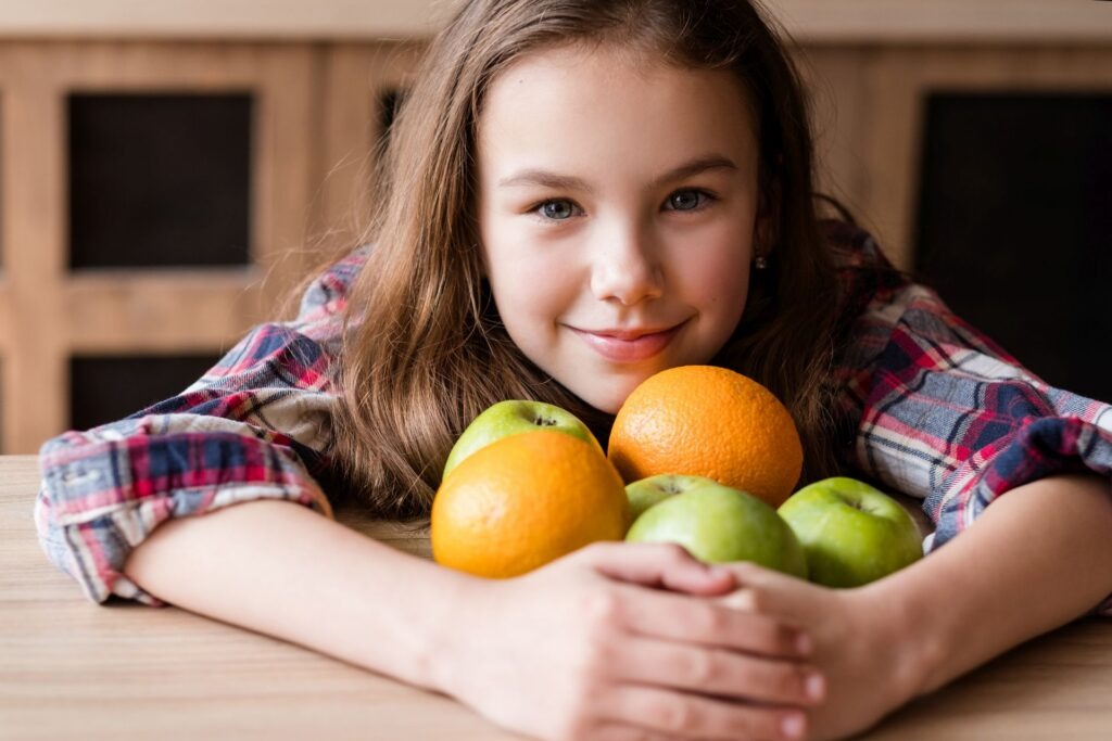 Kleines Kind mit Obst vor sich liegen.