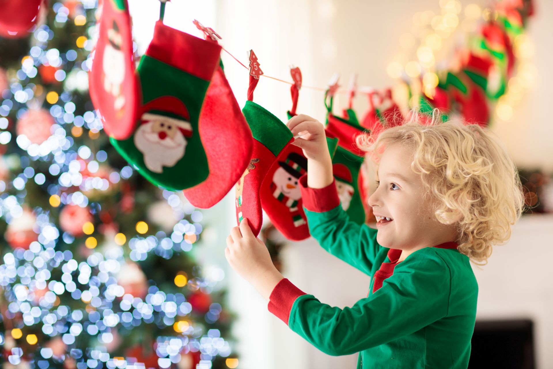 Kleines Kind steht laechelnd vor einem Adventskalender