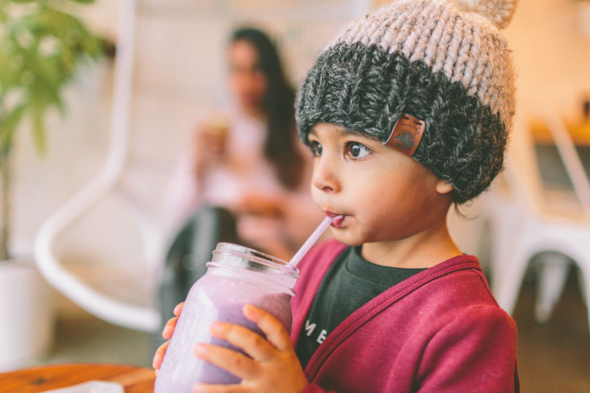 Kleines Kind hat einen Smoothie in der Hand und trinkt.