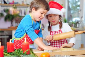 Kleines Maedchen und kleiner junge am Weihnachtsplaetzchenbacken.