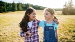 Zwei Kinder auf der Wiese, lachen sich an und halten sich im Arm.