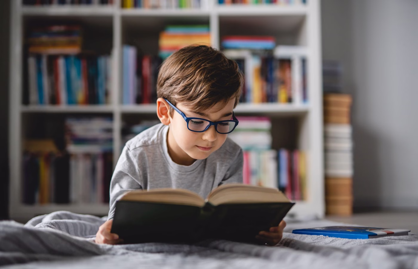 Junge mit Brille liest ein Buch.