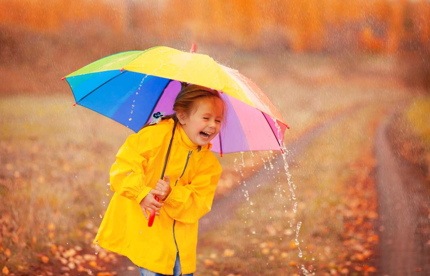 Kleines Mädchen mit Regenschirm im Regen