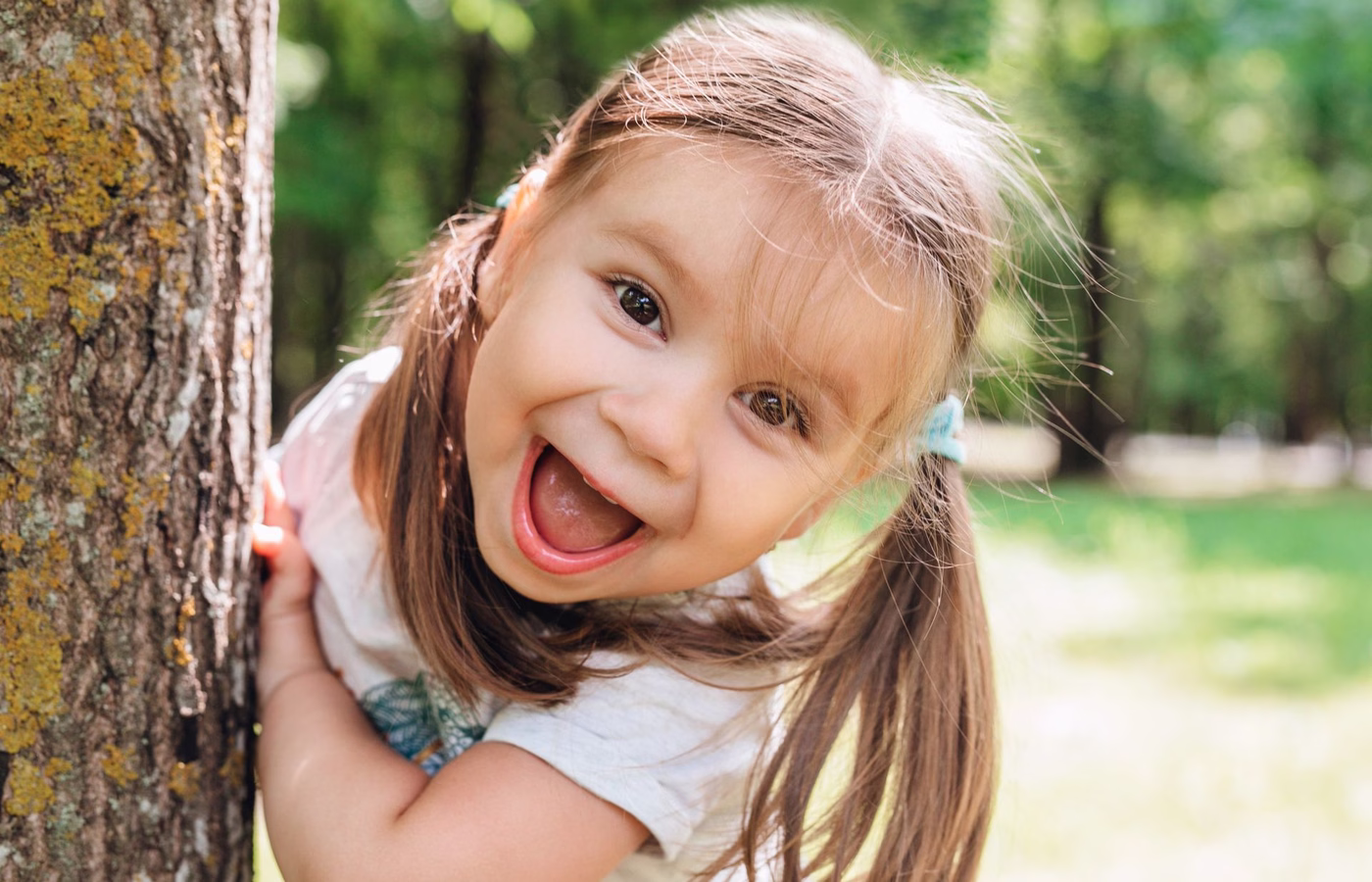 maedchen steht am baum und lacht